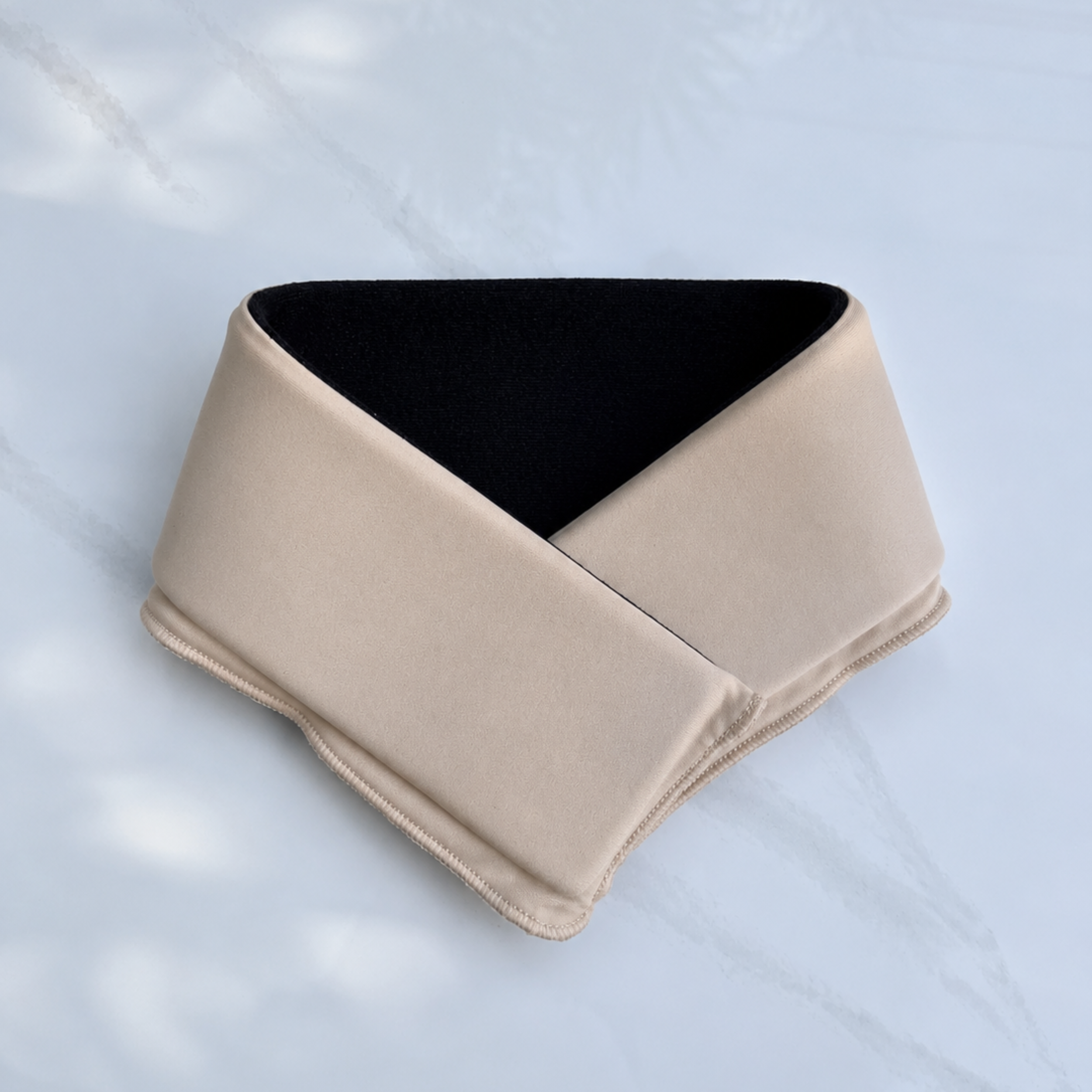 A latte beige cooling neck wrap, laid flat on a light marble-like surface.