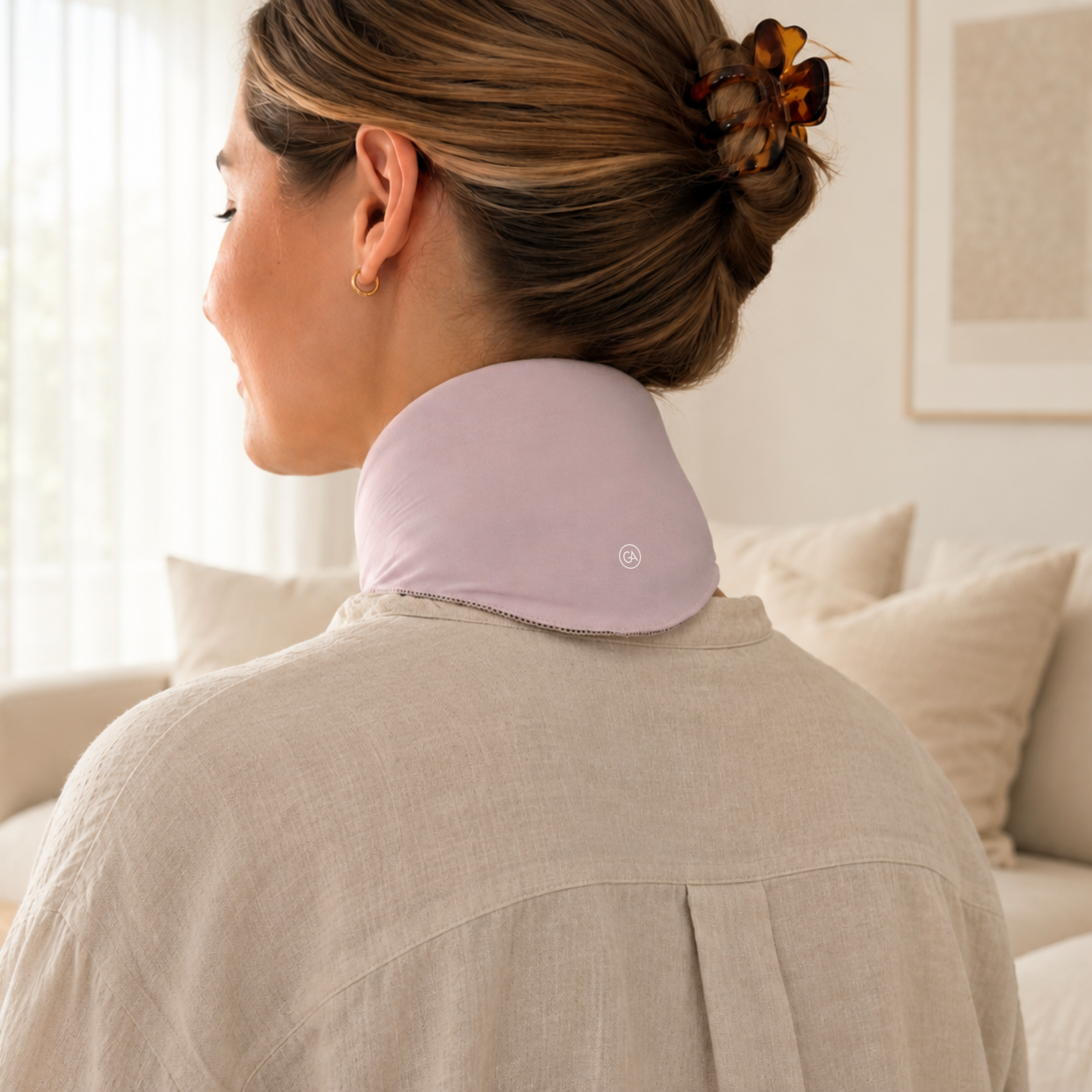 Woman wearing a pastel pink cooling neck wrap in a living room setting