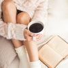 woman in pink sweater holding white mug