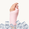 A close-up of a hand and wrist wearing a pastel pink cooling compression sleeve for thumb and wrist, with ice cubes around it on a plain light background.