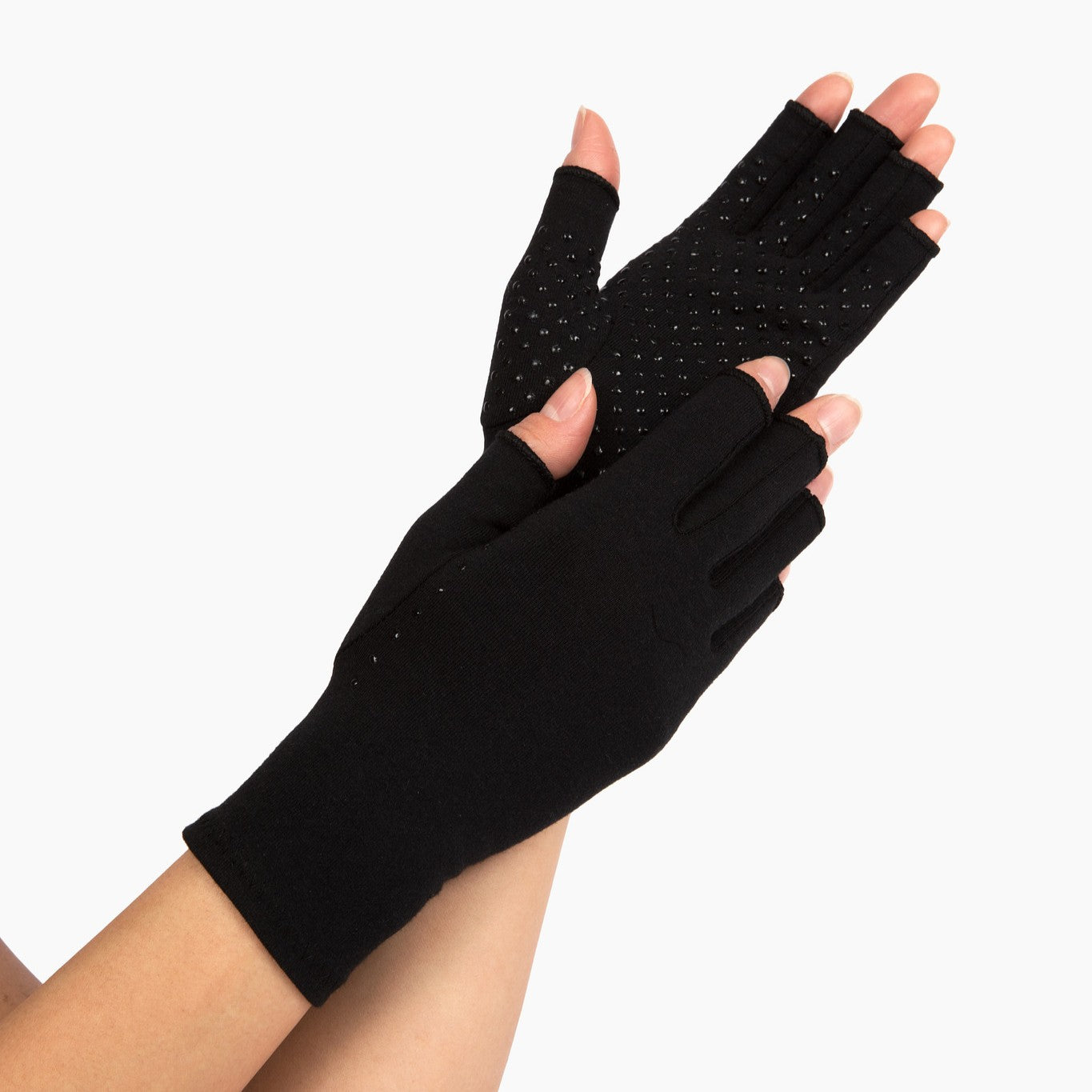 classic black compression gloves with silicone dots on palm worn by a pair of hands with arthritis on a white background