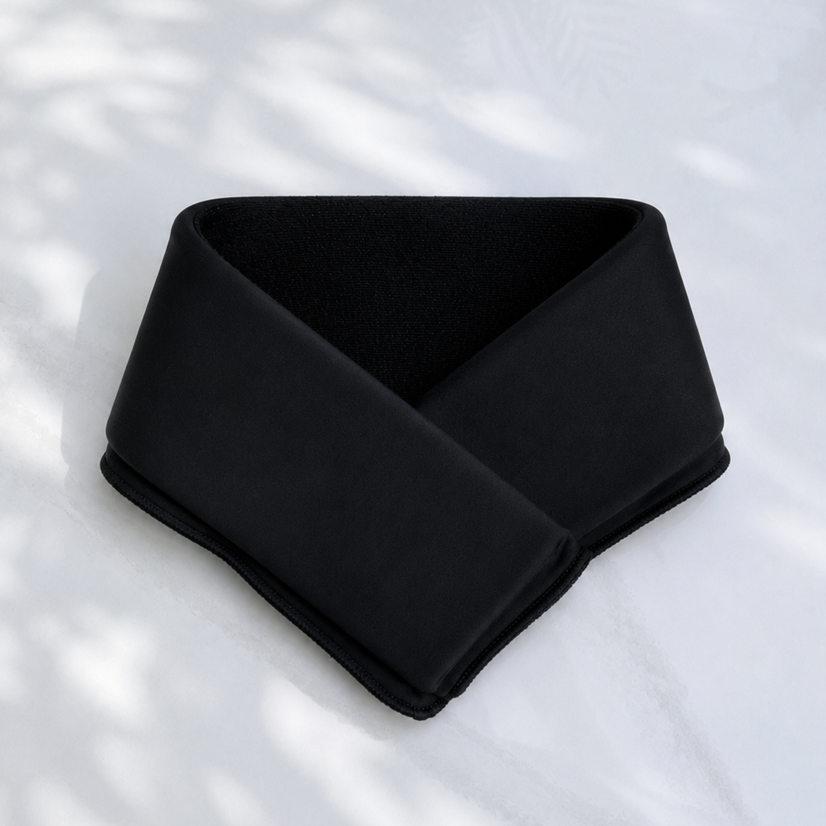 A jet black cooling neck wrap, laid flat on a light marble-like surface.