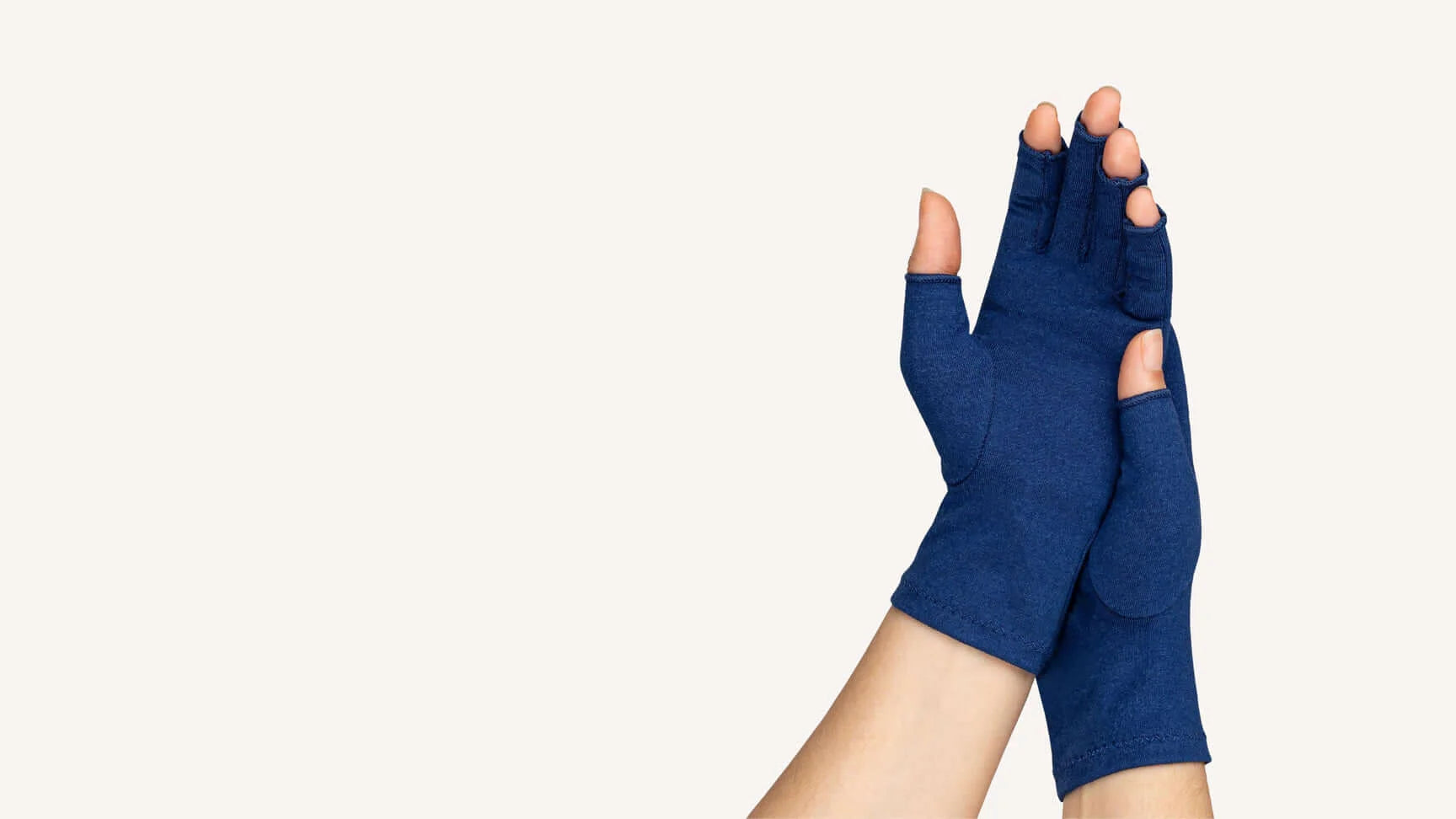 A woman with arthritis wearing Marine Blue Compression Gloves. Her hands are crossed with palms to the front.