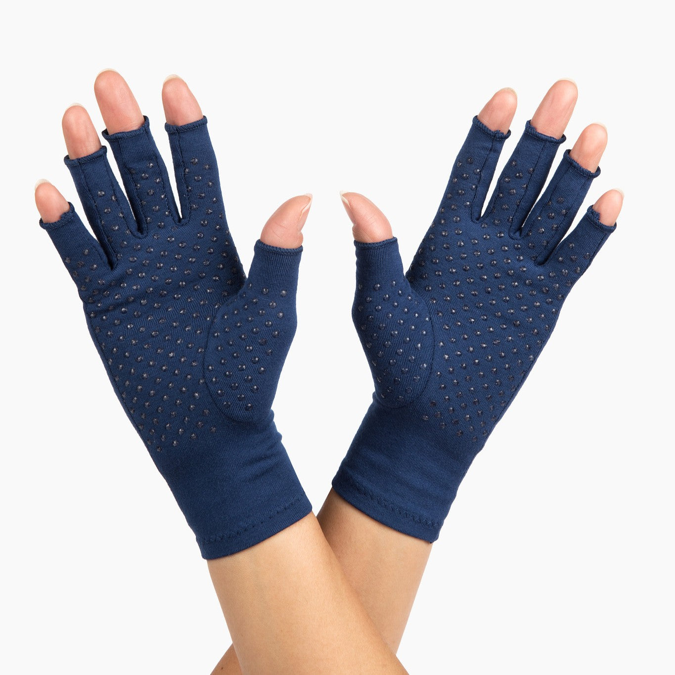 marine blue compression gloves with silicone dots on palm worn by a pair of hands with arthritis cross hands on a white background