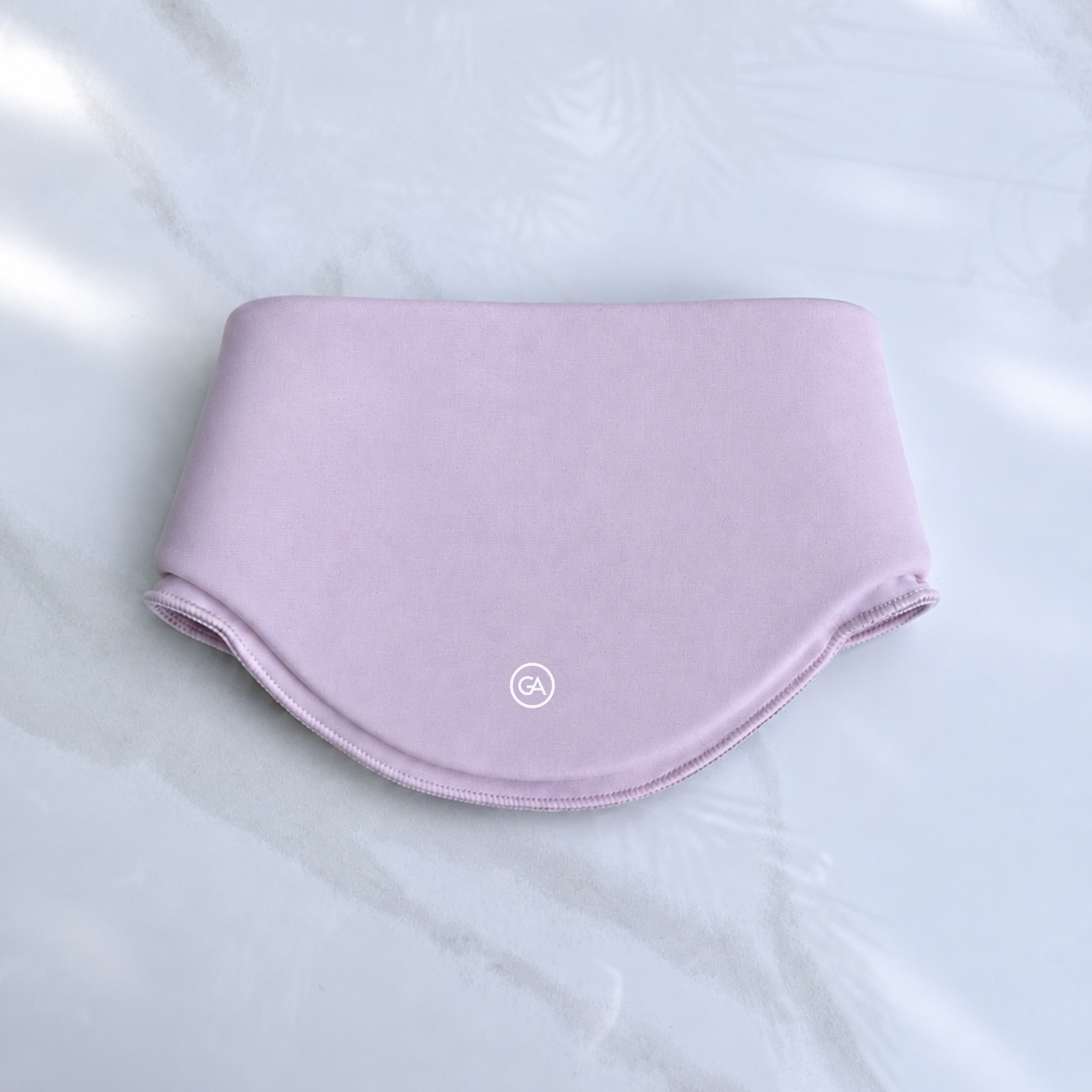 A pastel pink cooling neck wrap, laid flat on a light marble-like surface.