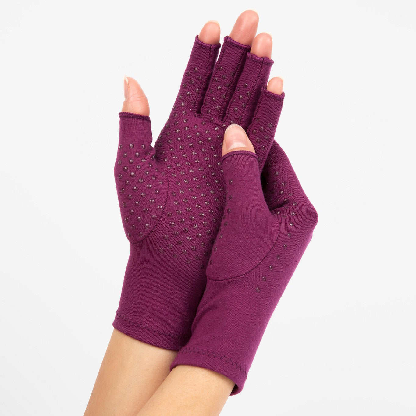 plum purple compression gloves with silicone dots on palm worn by a pair of hands with arthritis hands touching together on a white background