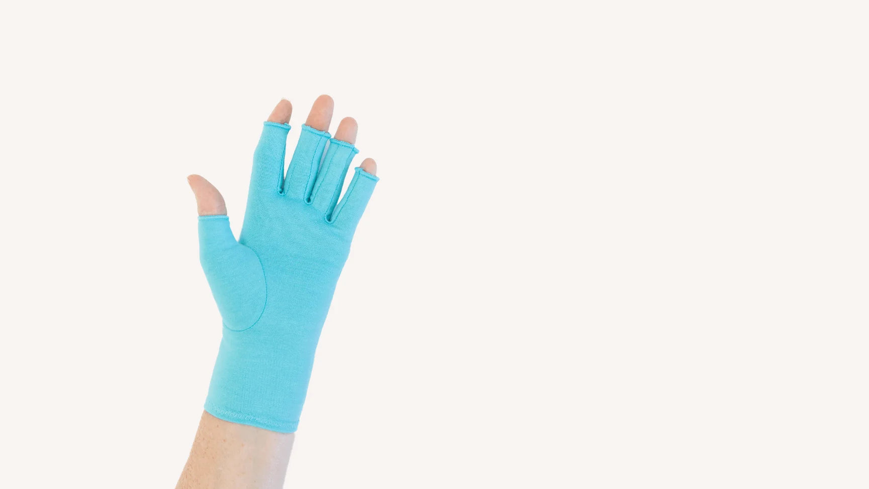 Close up of the hand of a woman with arthritis wearing Aqua Blue Compression Gloves on a beige background.
