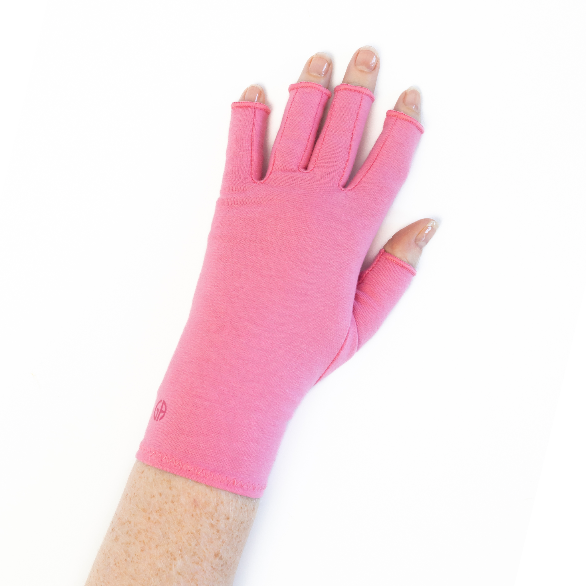 A close up of the hand of a woman with arthritis, wearing Coral Pink Compression Gloves and showing the back of her hand.