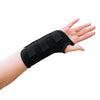 A woman with arthritis is showing the palm of her hand in close-up, wearing a Classic Black Wrist Brace with straps. The background is white